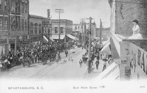 Reprinted from <a data-cke-saved-href='/Products/9780738502946' href='/Products/9780738502946'>Spartanburg, South Carolina</a> by Jeffrey R Willis (pg. 51, Arcadia Publishing, 1999). . In this 1904 photo from Spartanburg, South Carolina, a large crowd is gathered on the first block of East Main Street, while a woman overlooks the scene from the roof of a nearby two-story building.