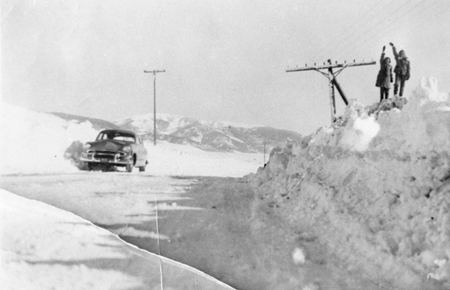 Children nearly reach the electrical wires on a snow bank in Crested Butte, Colorado.